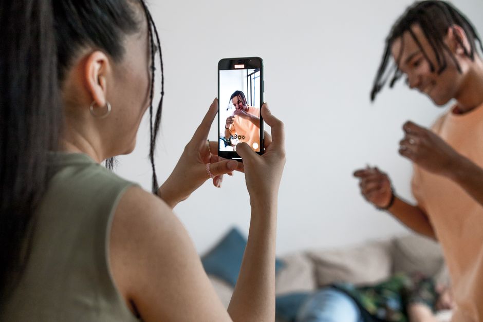 Persona joven usando smartphone, mostrando autenticidad y creación de contenido para potenciar su voz propia en redes sociales.